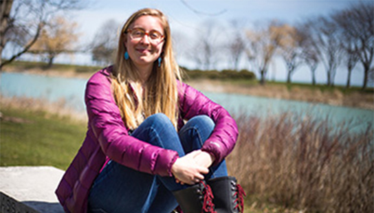 Katie Braun sits on a bench with the Lakefill in the background